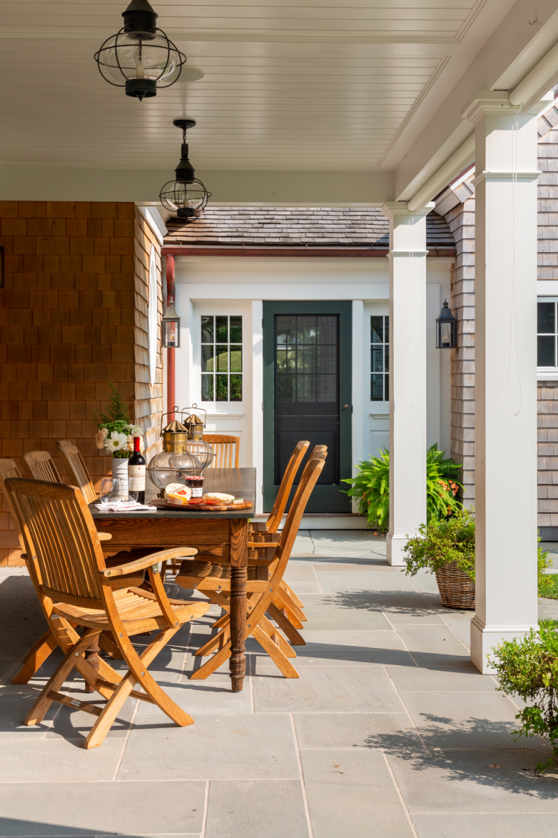 The back porch, generously proportioned, is designed for sitting and entertain- ing. The door at the end, painted Benjamin Moore Essex Green, connects to the mudroom, then the carriage house.